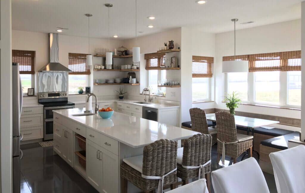 A kitchen with a large island and wicker chairs
