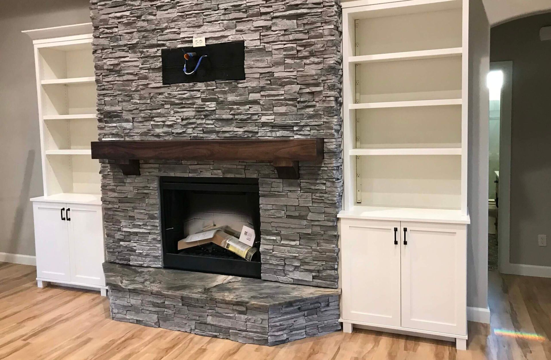 A living room with a fireplace , shelves and cabinets.