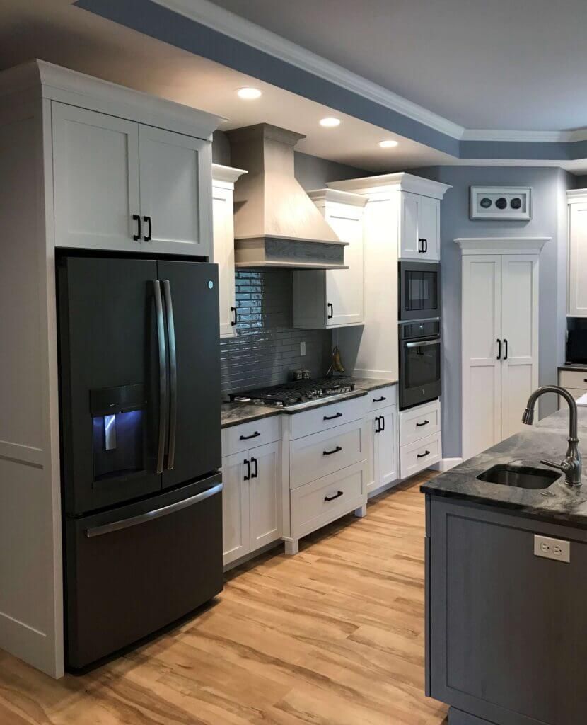 A kitchen with white cabinets , a black refrigerator , a stove , and a sink.