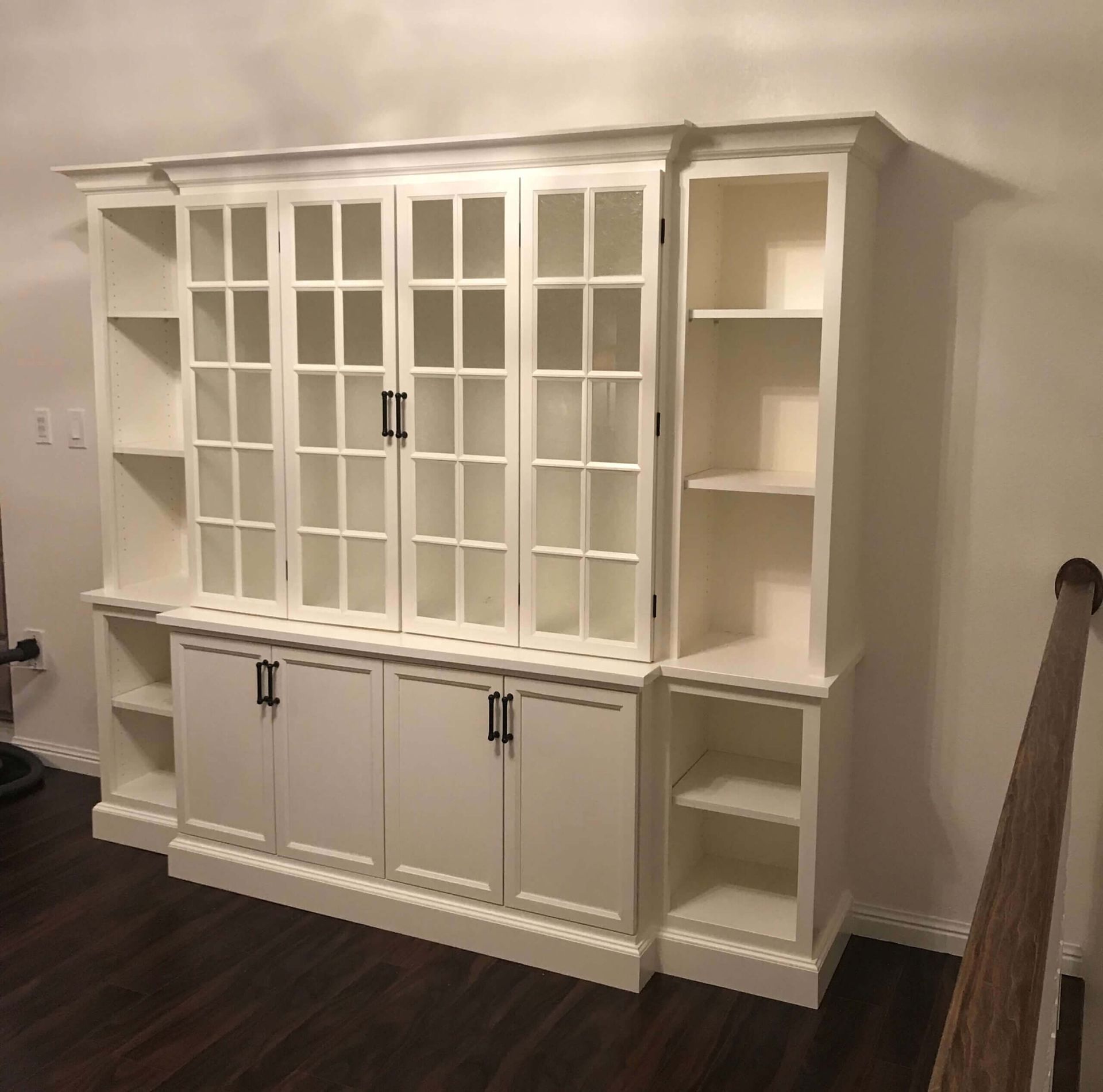 A large white cabinet with glass doors and shelves in a living room.
