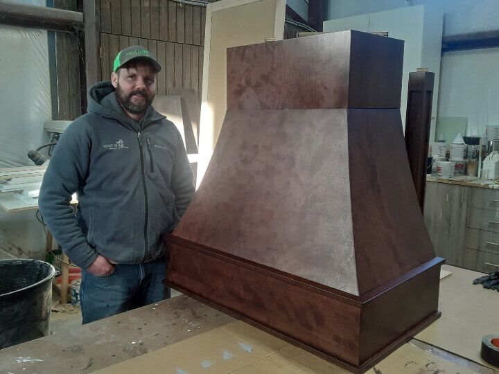 A man is standing next to a large wooden box on a table.