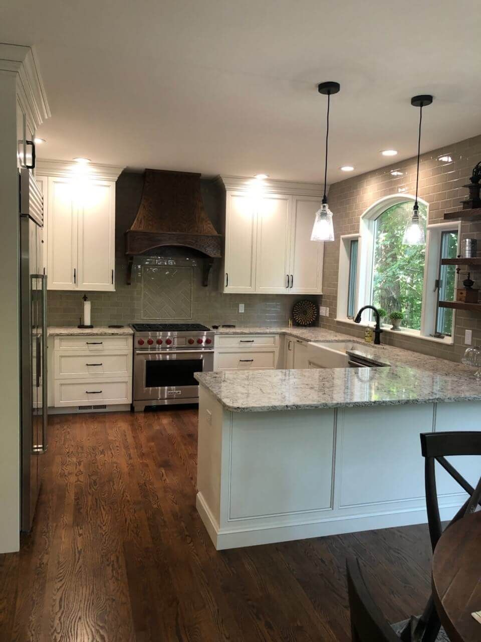 A kitchen with white cabinets , stainless steel appliances , granite counter tops and hardwood floors.
