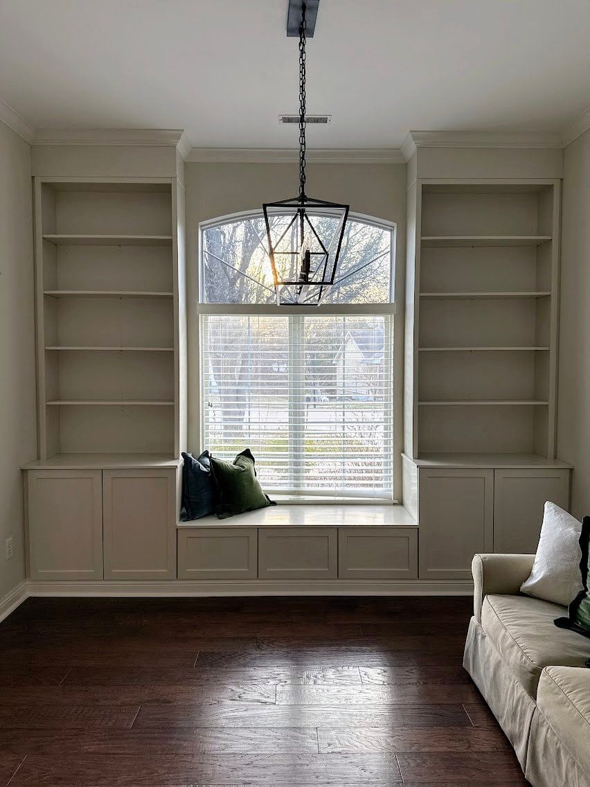 A living room with a couch , shelves , and a window seat.