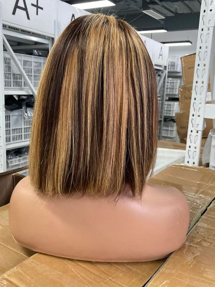 Bob wig on a mannequin head, brown and blonde highlights, in a warehouse setting.