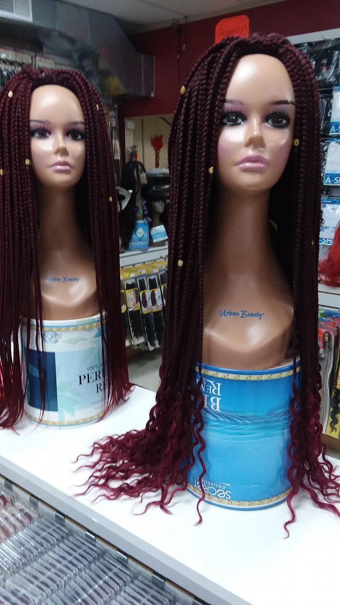Two mannequin heads with long, red braided wigs on display in a store.