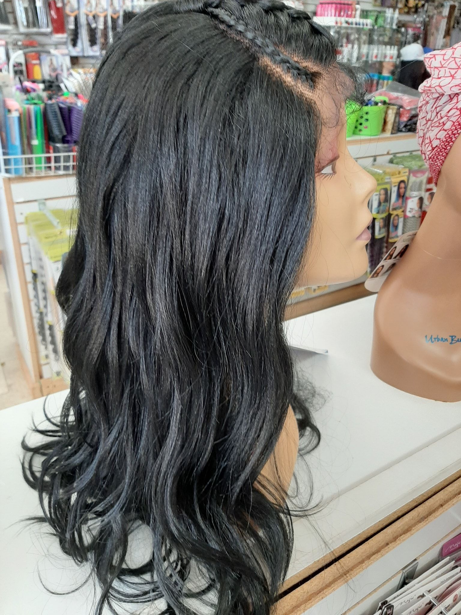 Black wig on a mannequin head, with braided accents on the side and wavy hair.