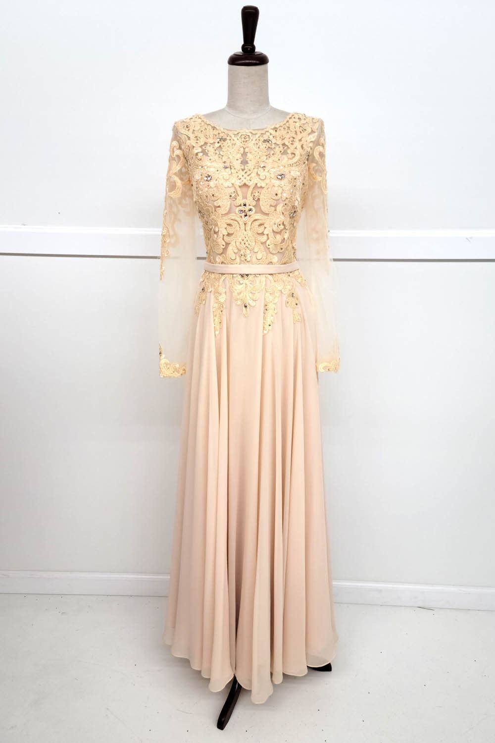 Beige formal gown on a mannequin, with gold lace bodice and long sheer sleeves.