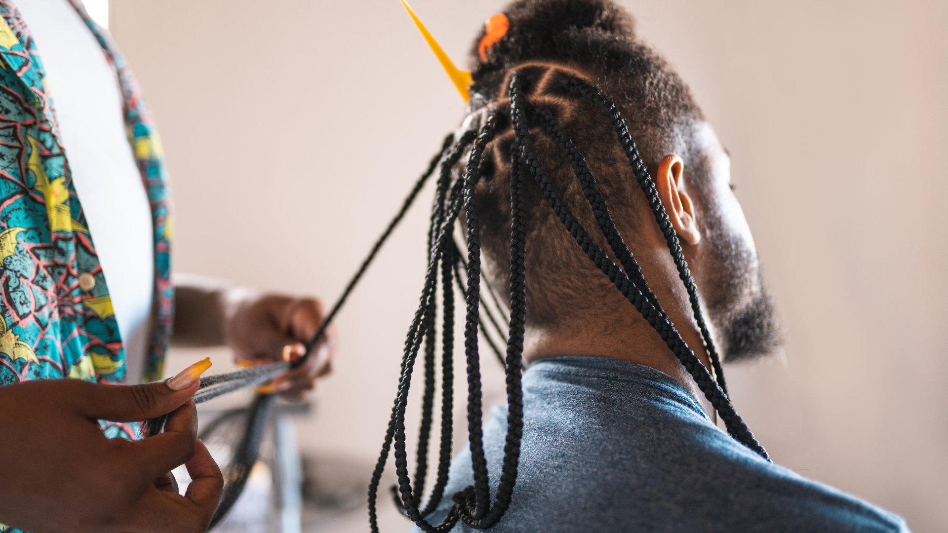 Person getting hair braided by another person. Braiding black hair.