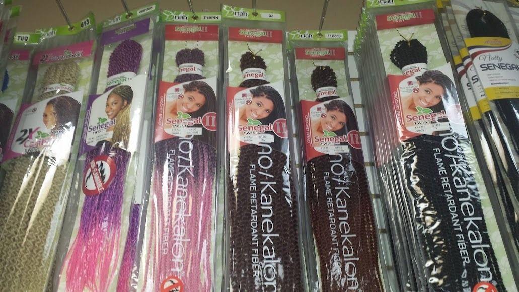 Braiding hair packages in various colors, displayed on a shelf.