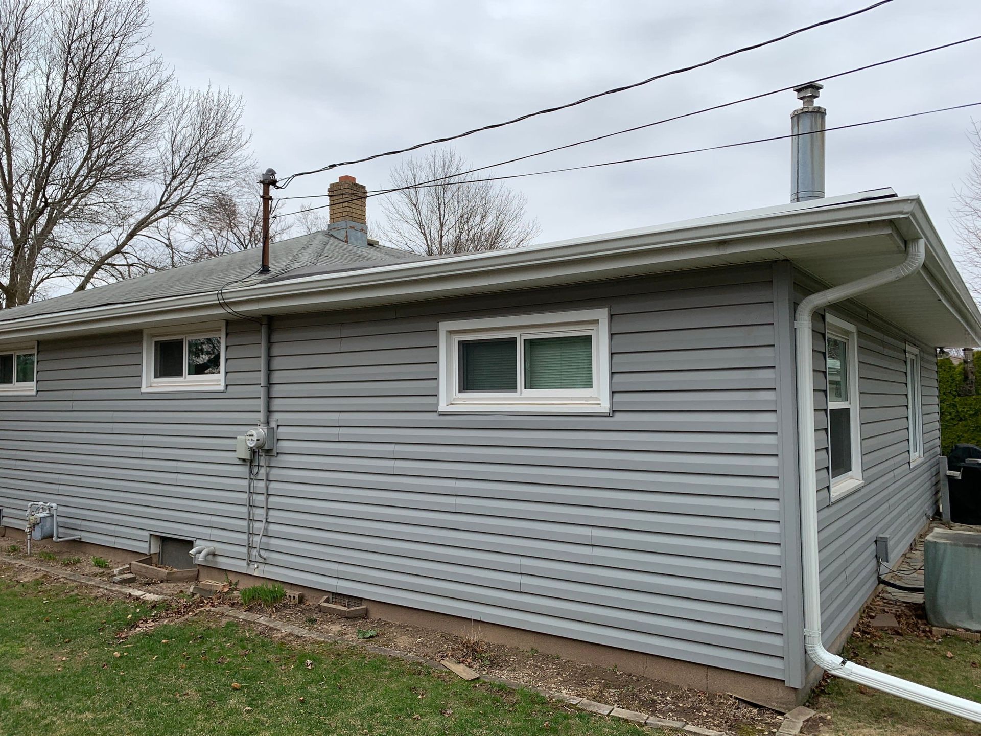 A small gray house with a chimney on the roof.