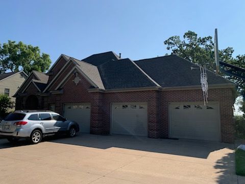 A white suv is parked in front of a large brick house