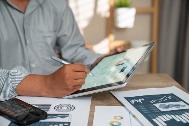 A man is sitting at a table using a tablet computer.