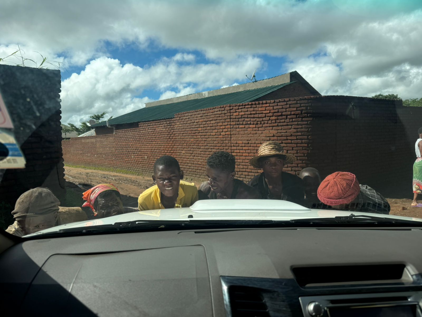 7 boys and meme from a village in malawi come together to help dig out a white truck from the mud after heavy rainfall.