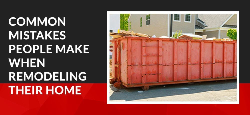 A large orange dumpster is sitting in front of a house.