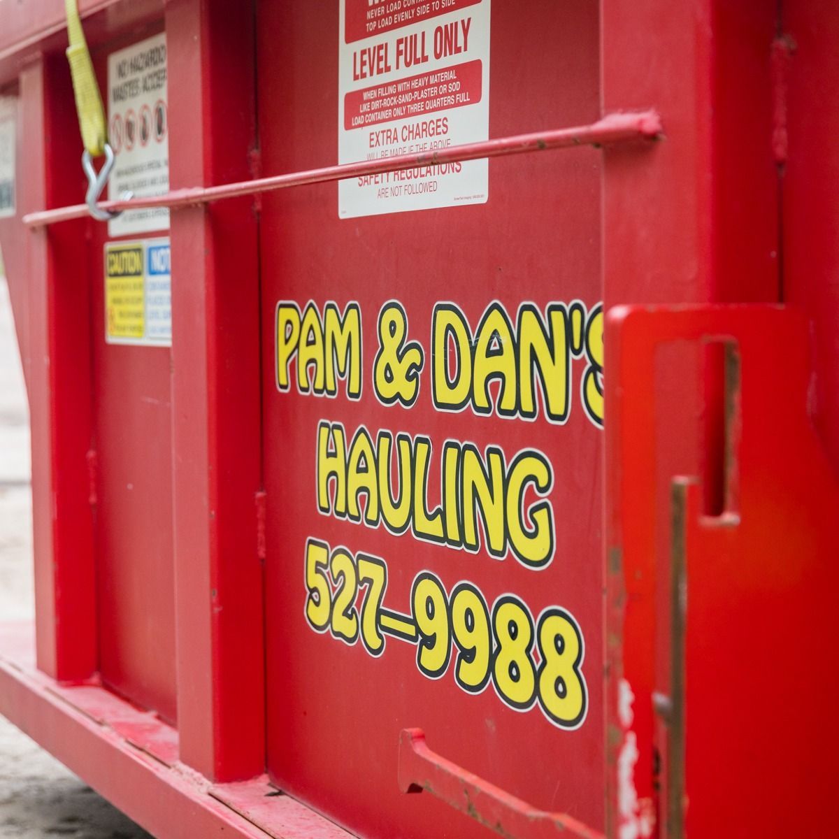 A red dumpster from pam and dan 's hauling