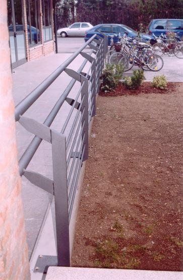 Una fila di biciclette è parcheggiata dietro una ringhiera metallica