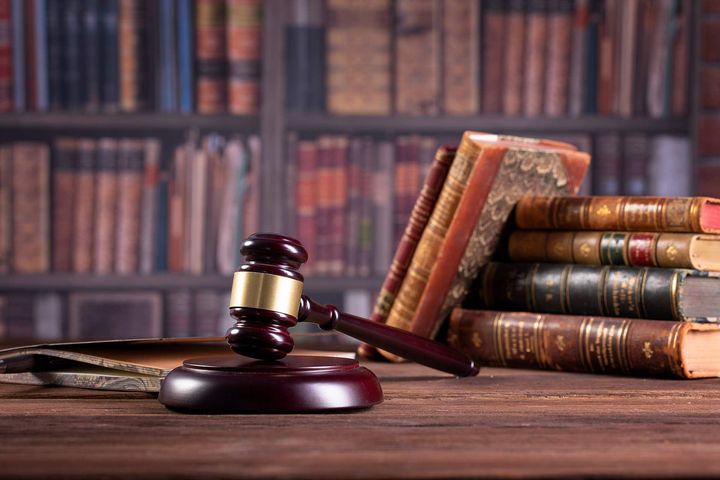 A judge 's gavel is sitting on a wooden table next to a stack of books.