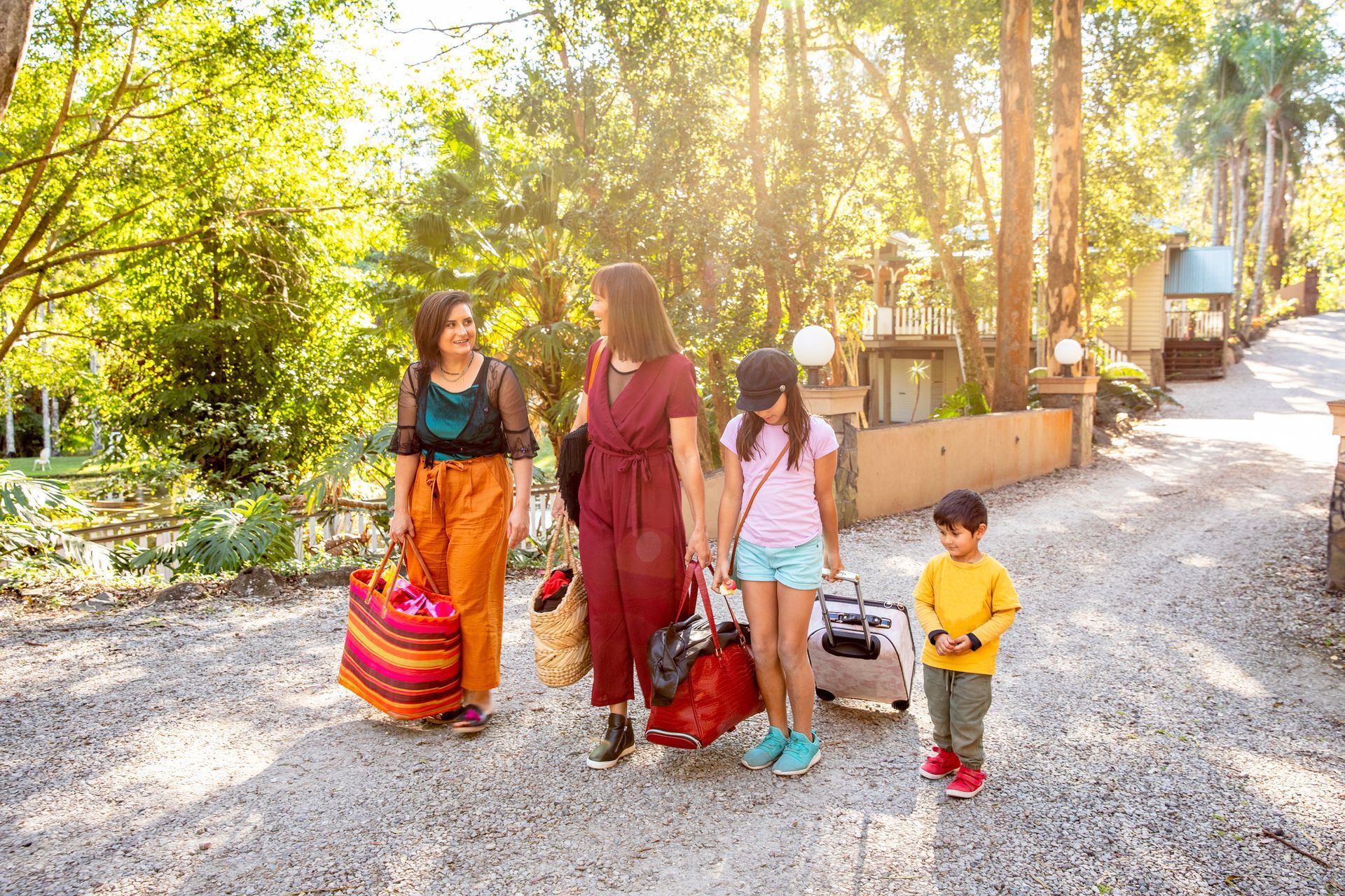 A group of people are walking down a dirt road with luggage.