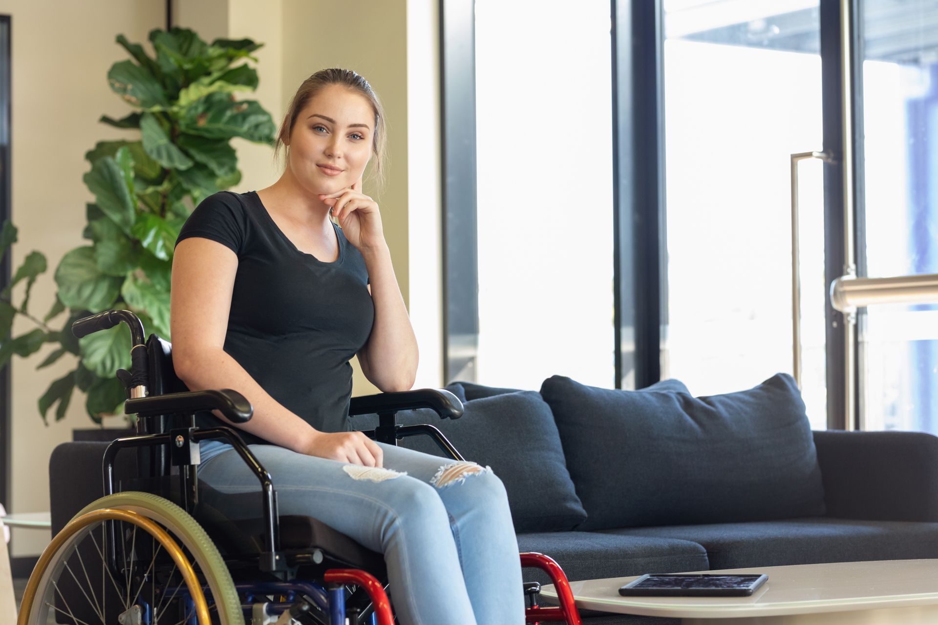 A woman in a wheelchair is sitting on a couch in a living room.
