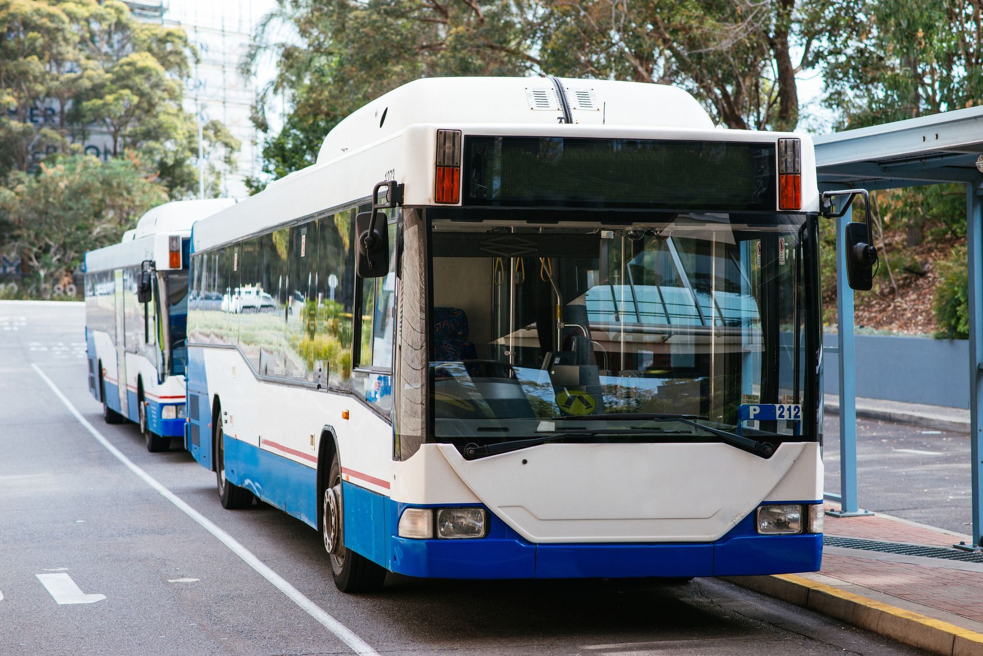 A blue and white bus is parked at a bus stop.