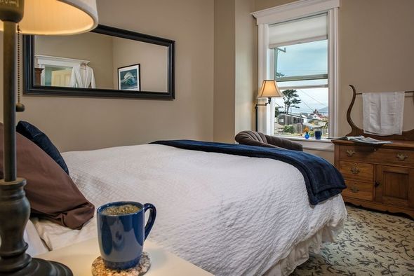 A bedroom with a bed , lamp , mirror and dresser.