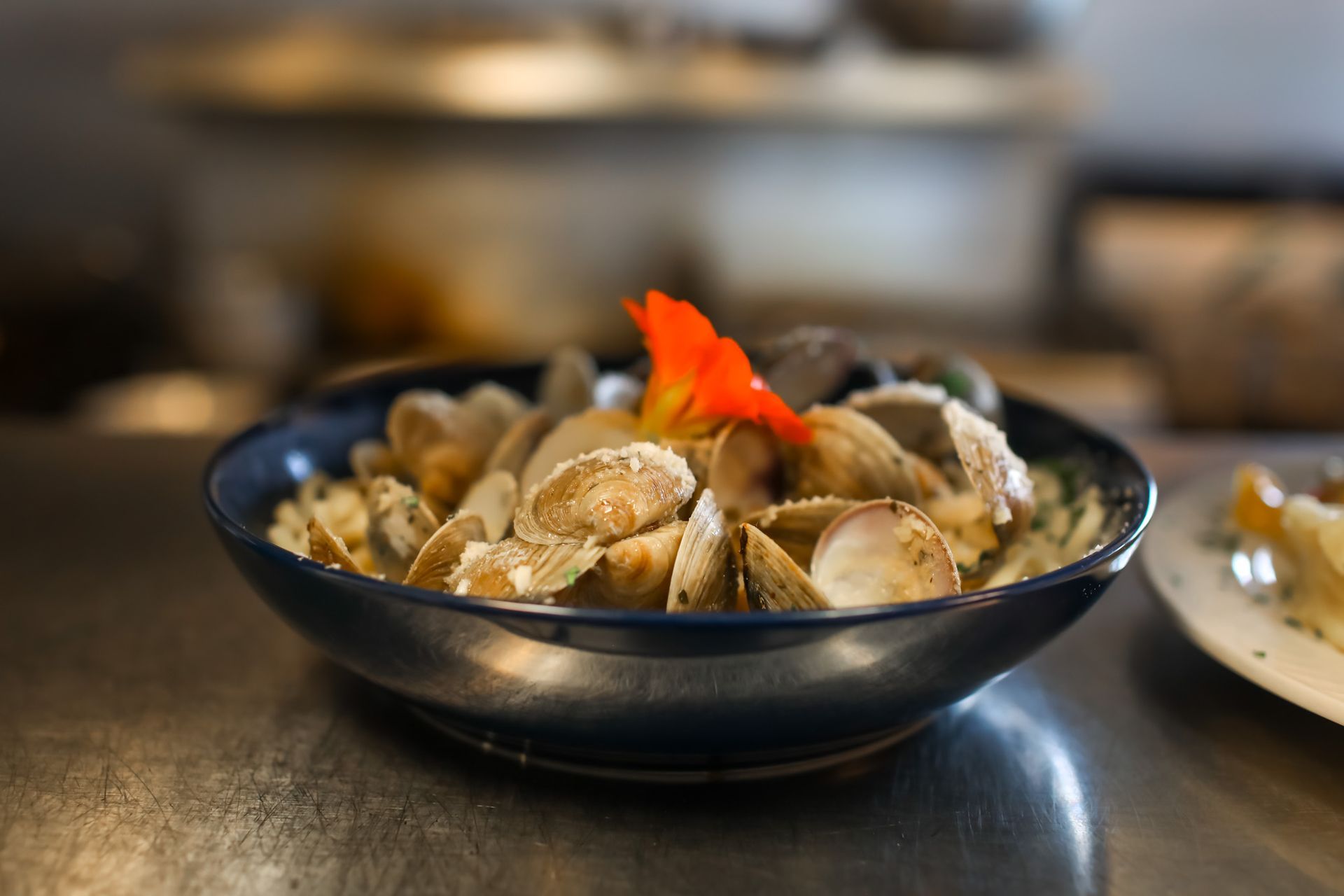 A close up of a bowl of clams on a table.