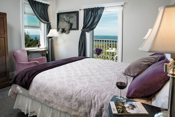 A bedroom with a king size bed and a glass of wine on the nightstand.