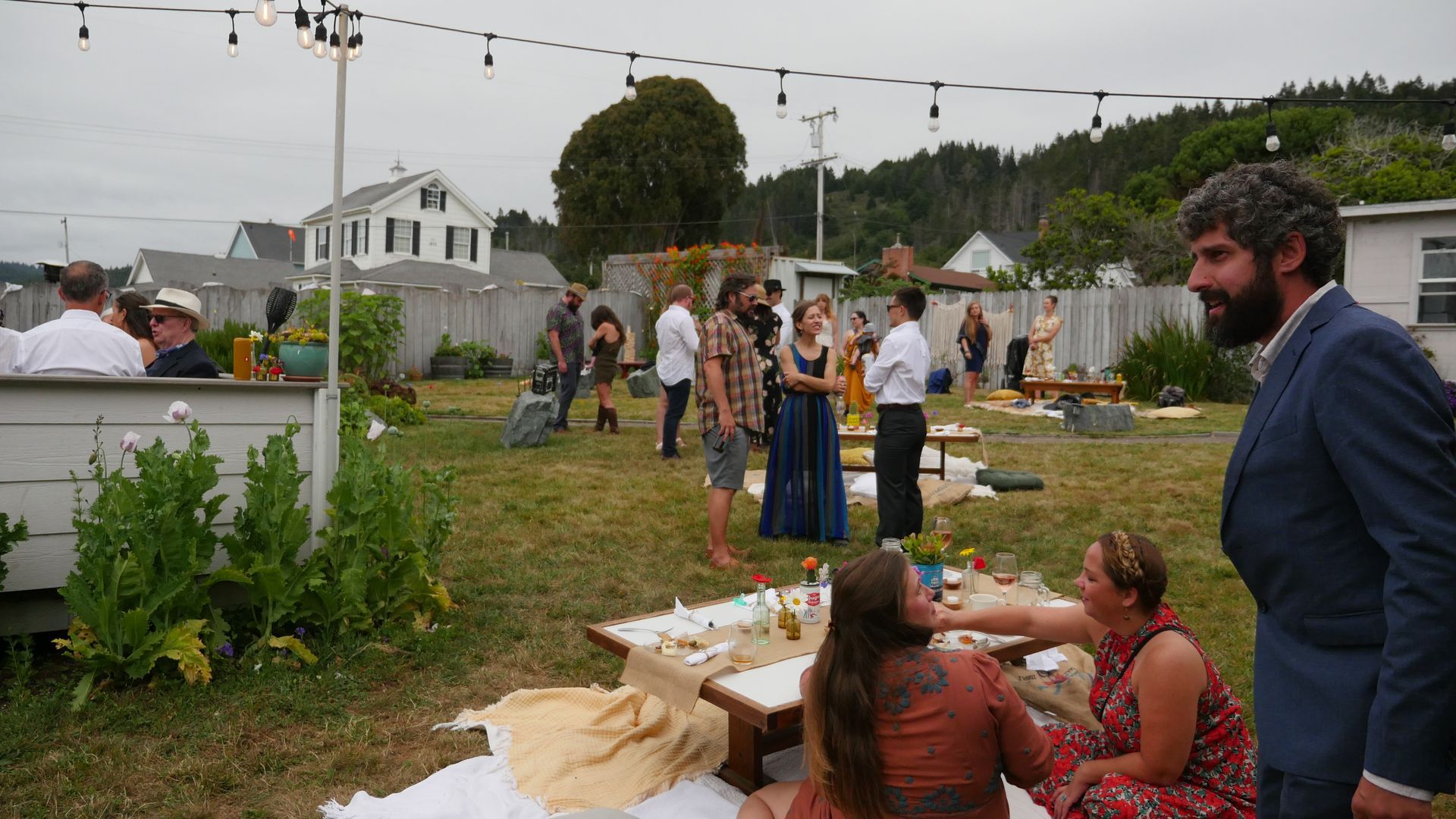 A group of people are having a picnic in a backyard.