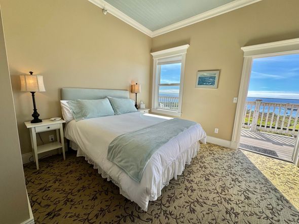 A bedroom with a king size bed and a view of the ocean.