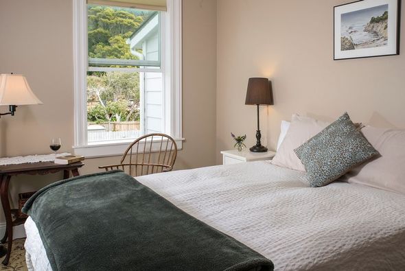 A bedroom with a bed , chair , lamp and window.