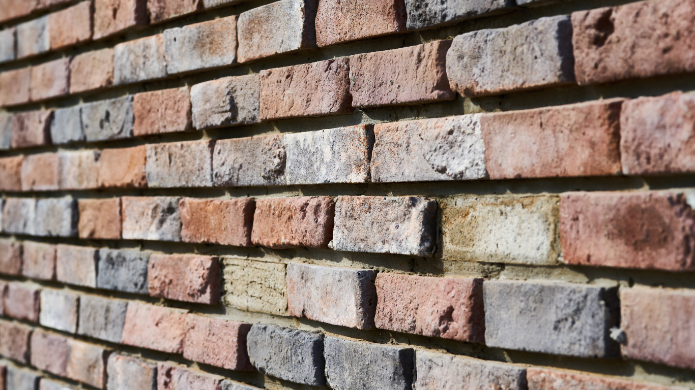Close-up of a brick wall with red, brown, and gray bricks.