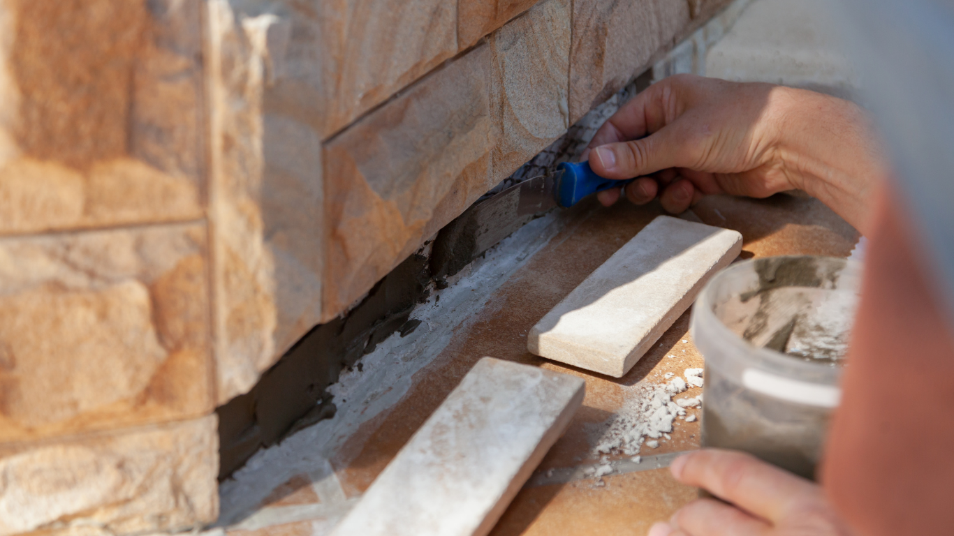 Person applying grout between stone tiles with a tool.