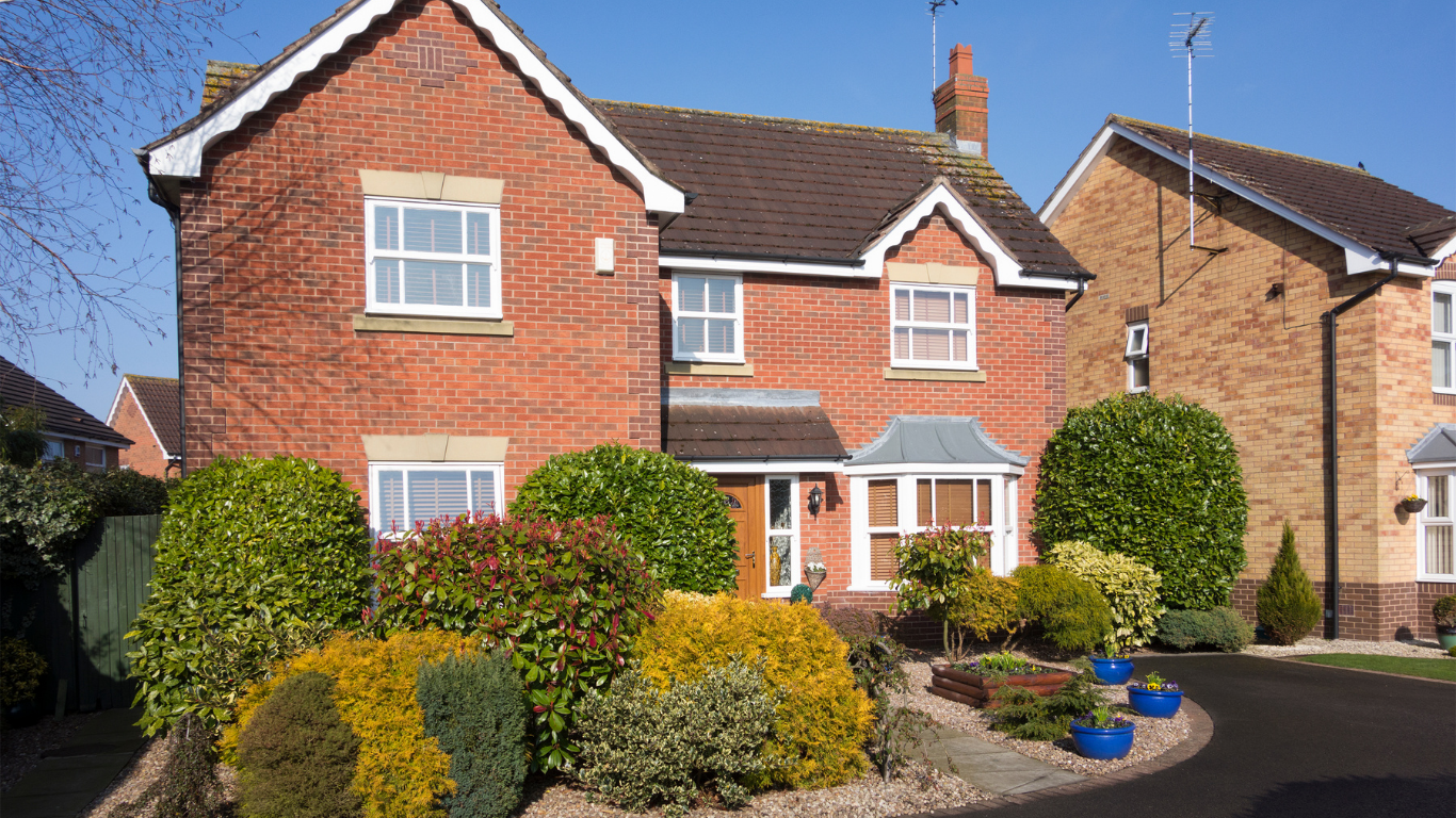 Red brick house with manicured landscaping and blue skies.