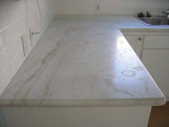 A white marble counter top in a kitchen that has stains and etch marks.