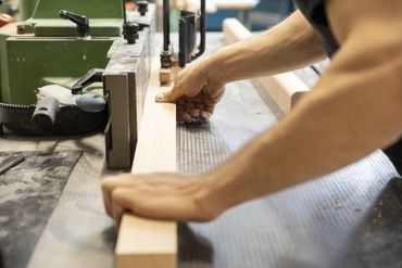 Ein Mann schneidet ein Stück Holz auf einer Maschine.