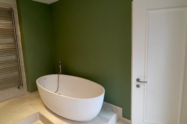 Ein Eimer orangefarbener Farbe mit einem Pinsel darin