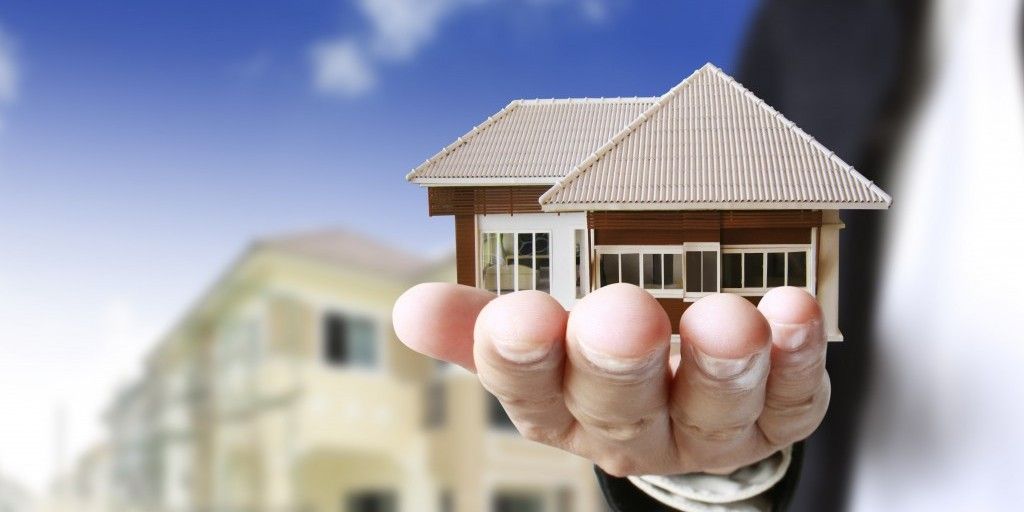 A person is holding a small model house in their hand.