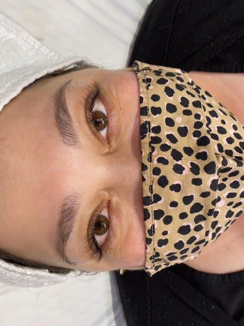 Person with brown eyes wearing a cheetah print face mask, with long eyelashes and light eyebrows.