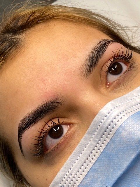 Close-up of a person's eyes, dark eyebrows, and eyelashes, wearing a blue face mask.