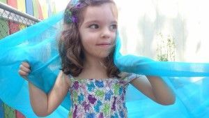 A little girl is holding a blue cloth over her head.