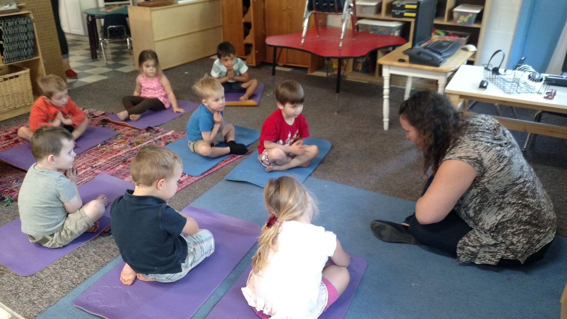 A group of children are sitting on yoga mats in a circle