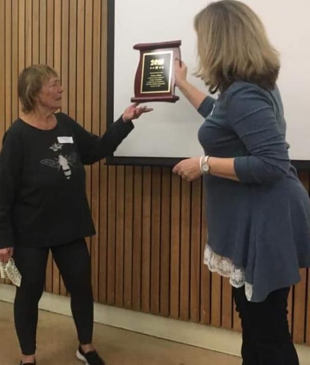 Two women standing next to each other holding a plaque that says 2010 on it