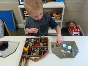 A young boy is sitting at a table playing with toys.