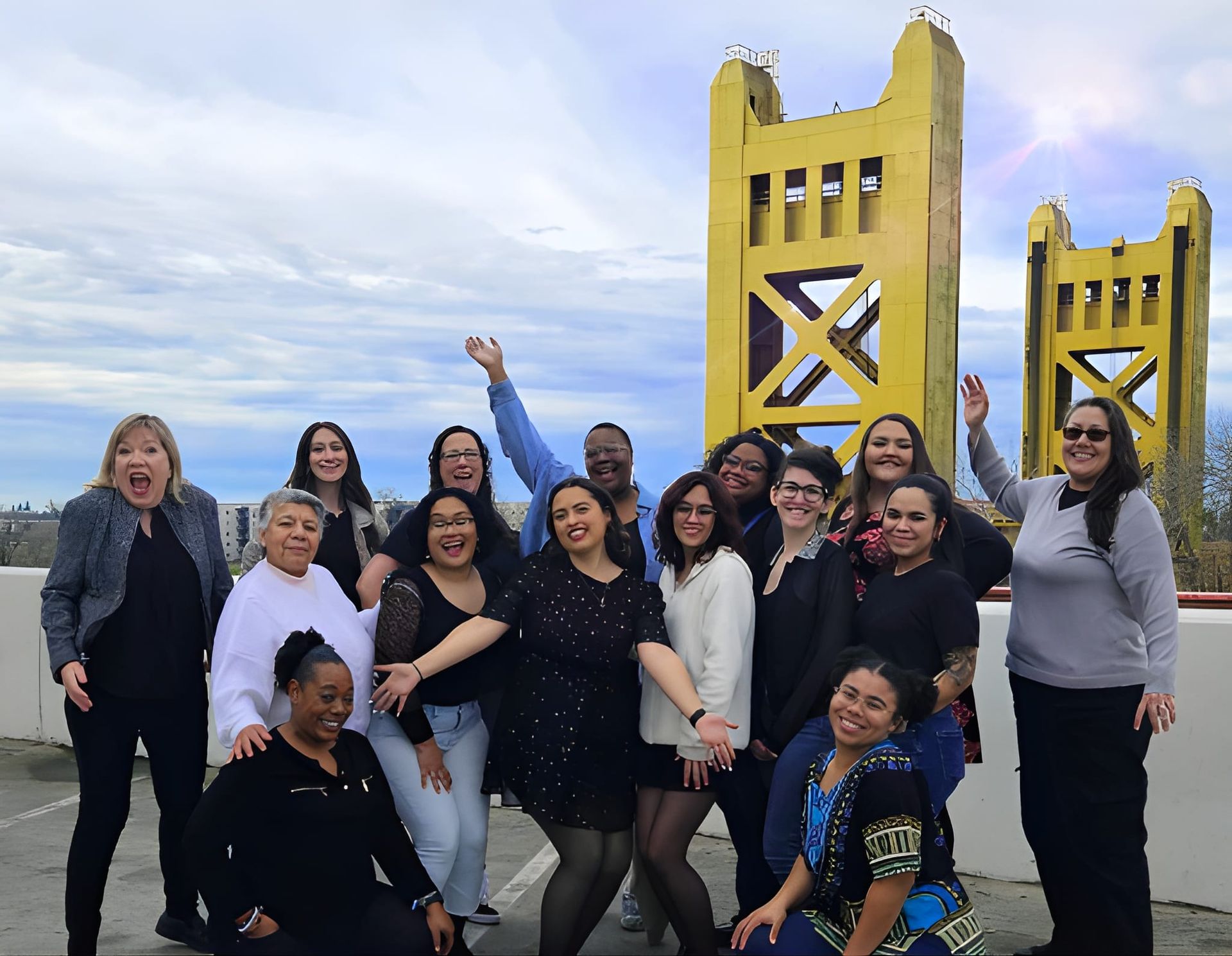 A group of women are posing for a picture in front of a yellow bridge.