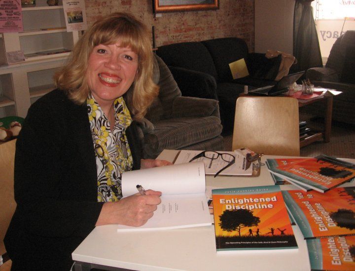 A woman sits at a table with a book titled enlightened discipline