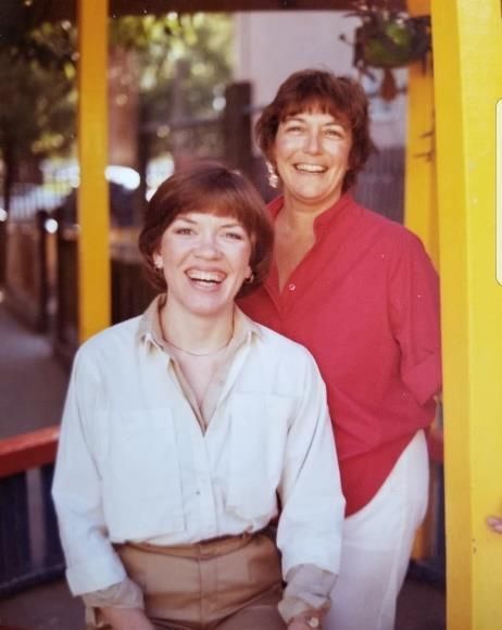 Two women posing for a picture in front of a yellow building