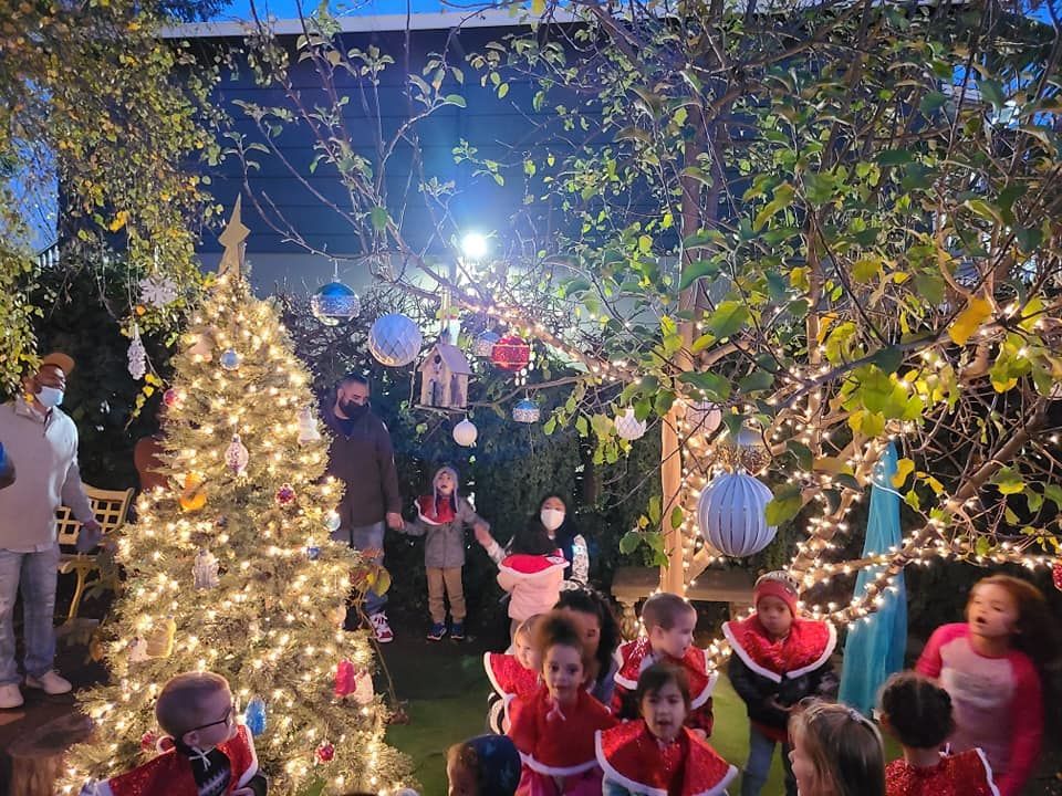 A group of children are standing in front of a christmas tree.