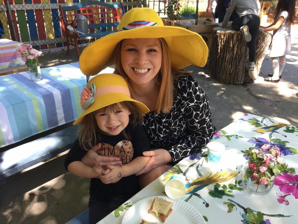 A woman and child wearing yellow hats are sitting at a table