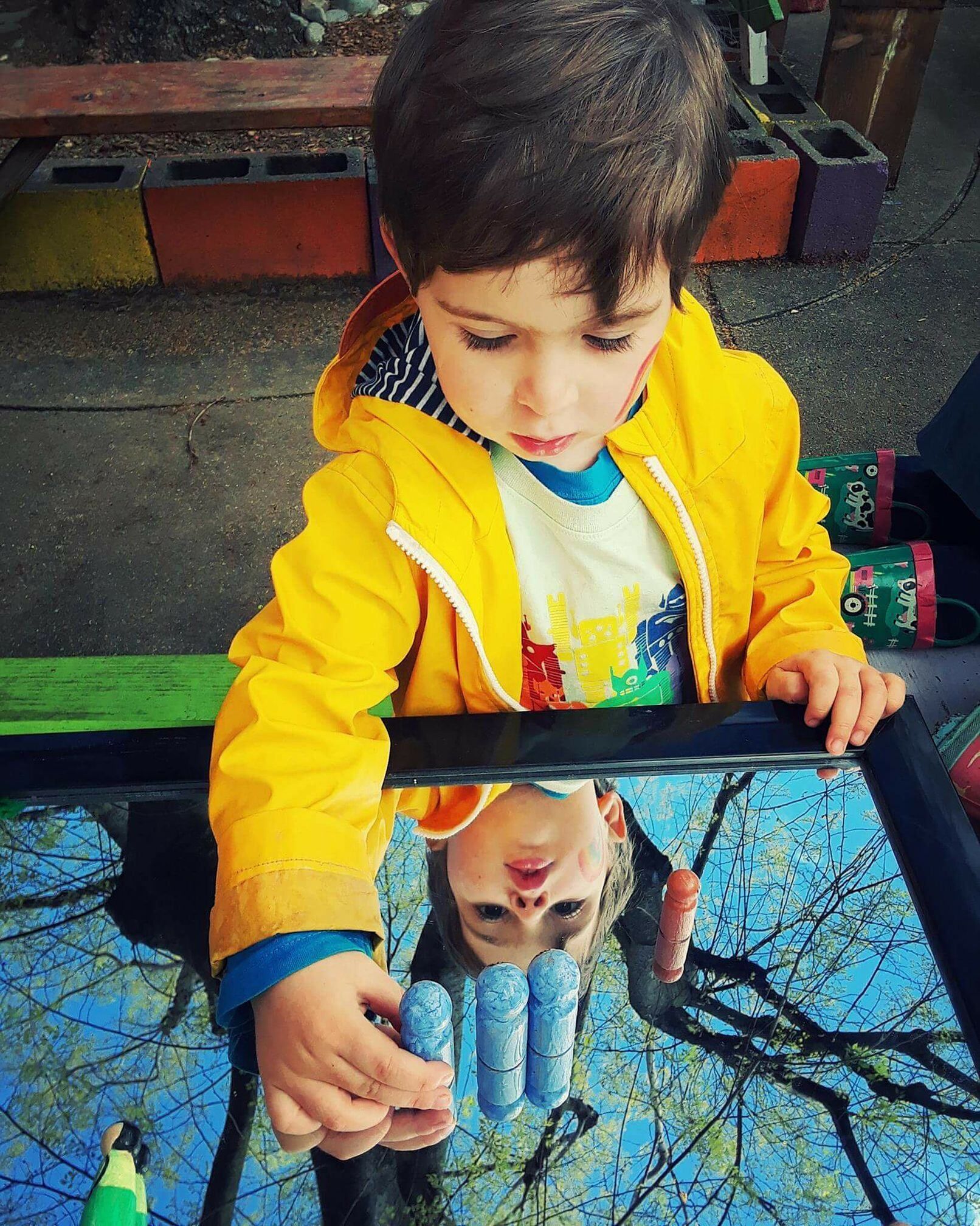 A young boy is looking at his reflection in a mirror