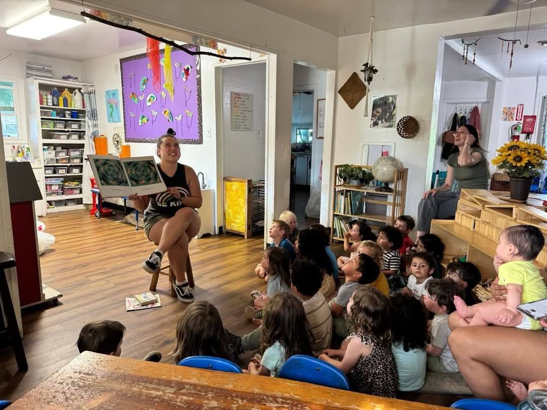 A woman is reading a book to a group of children in a classroom.